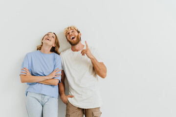 White blond excited couple pointing finger upward and laughing