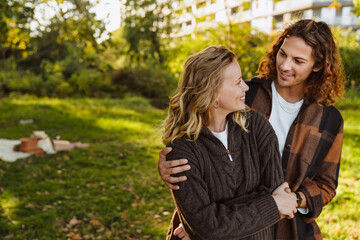 Obraz premium White happy couple smiling and hugging together while walking in park