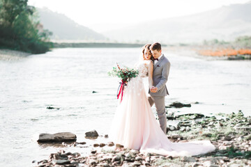 Fototapeta na wymiar Wedding couple, groom and bride hugging, outdoor near river