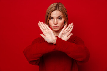 Young blonde woman showing stop gesture with crossed hands isolated