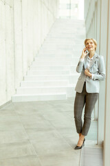 Businesswoman using mobile phone on modern office hallway