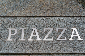 Close-up of engraved word Piazza at pavement at Novartis Campus at City of Basel on a cloudy autumn day. Photo taken October 3rd, 2022, Basel, Switzerland.