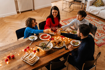 Big happy family having christmas dinner while sitting by table at home