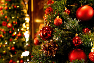 Fototapeta na wymiar Close up of Christmas tree and balls. Bokeh garlands in the background. New Year and christmas concept with copy space. Wooden new year background, green tree, red berries