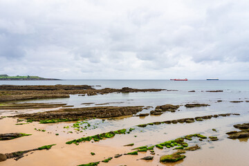 Empty beach with rock under cloudy day with sand and cliff, Spain