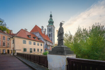 Fototapeta na wymiar Lazebnicky Bridge with John of Nepomuk Statue and former Church of Saint Jost Tower - Cesky Krumlov, Czech Republic