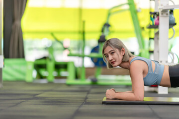 Strong young woman doing push-ups in gym. Fit female exercising in health club.