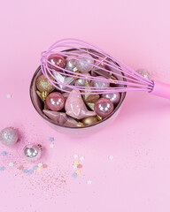 New Years toys of pink and gold color lie on a pink plate .Pink whisk for whipping. Gold sparklrs on a pingc background  4
