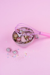 New Years toys of pink and gold color lie on a pink plate .Pink whisk for whipping. Gold sparklrs on a pingc background  3
