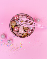 New Years toys of pink and gold color lie on a pink plate .Pink whisk for whipping. Gold sparkls on a pink background