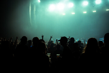 Fototapeta na wymiar People in silhouette at a concert with green lighting and darkened foreground
