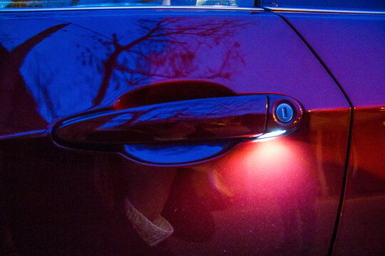 Door Handle Of Red Car With Keyhole Illuminated At Night