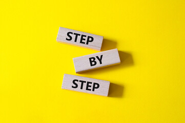 Step by step symbol. Wooden blocks with words Step by step. Beautiful yellow background. Business concept. Copy space.