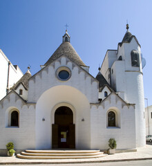 Fototapeta na wymiar Fachada de la iglesia de San Antonio de Padua en Alberobello, Italia. Iglesia con una arquitectura similara a los trullos, con su cúpula conica de piedras apiladas.