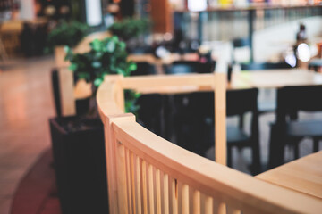View of modern food court food hall interior in the big shopping mall, different fast food cafes and restaurants with wooden and plastic tables and chairs, customers order food in the background