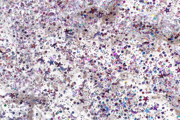Texture cosmetic gel with glitters as background. Purple glitter for face, body, hair. Shimmer cosmetic gel for festive make up, aesthetic beauty product texture, sparkles in form star, moon