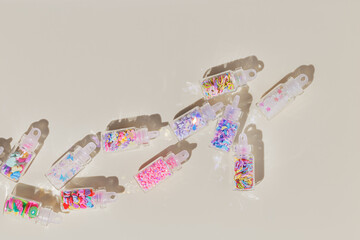 Set colored glitters for nail art and makeup in glass jars on beige background. Trend Flat lay with glitter for nails in bottles with sahdows and glare, visual for manicure, creative layout