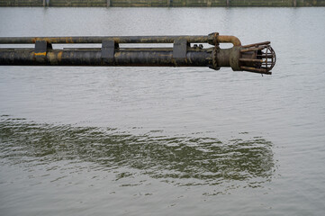 Side view of a dredge drag head of a suction dredge barge above water in harbor