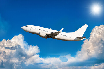 Naklejka na ściany i meble White passenger jetliner flying in the air above scenic clouds