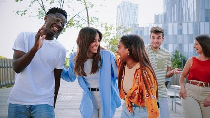 Group of young multiracial friends smiling and walking in university campus. At background a couple of students speaking and having fun together. High quality 4k slowmotion footage