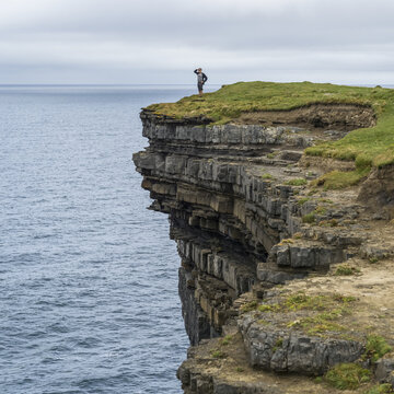 A male tourist stands looking out over the ocean from Downpatrick Head, West coast of Ireland; Killala, County Mayo, Ireland