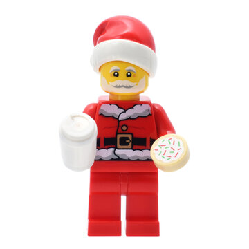 Lego minifigure of Santa Claus with milk glass and cookie in hand closed up isolated on white. Editorial illustrative image of popular plastic toy constructor.