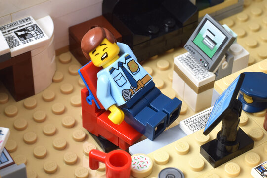 Lego minifigure of police officer is sleeping in the office. Editorial illustrative image of law and punishing. Studio shot.