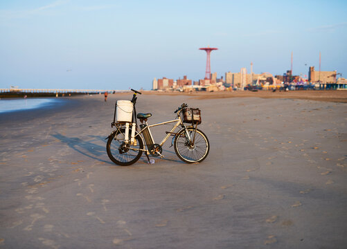 Fisherman&acirc;&euro;&trade;s bicycle on Coney Island Beach with Luna park in background; New York City, New York, United States of America