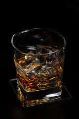Glass of whiskey with ice on a black background. Strong alcoholic drink