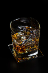 Glass of whiskey with ice on a black background. Strong alcoholic drink