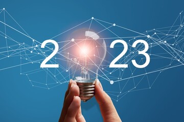 Numbers 2023 and light bulb in hands