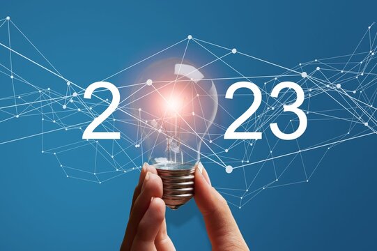 Numbers 2023 and light bulb in hands