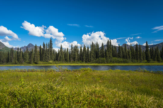 Clouds rolling across mountain peaks in the Talkeetna Range in South-central Alaska on a sunny summer day; Alaska, United States of America