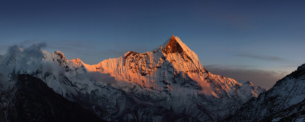 Snow capped Mt. Machapuchare colored by last rays of sun, view from Annapurna base camp. Himalaya mountains, Nepal.