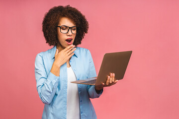 Young african american tired serious sad business woman with curly hair using laptop isolated over pink background.