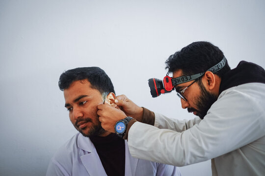 South asian medical student practicing ent examination on each other wearing white apron 
