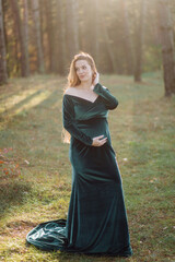 Pregnant happy young woman walking outdoors in forest