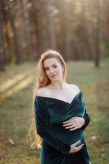 Pregnant happy young woman walking outdoors in forest