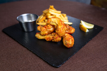 spicy shrimp with spices and lemon on a black plate