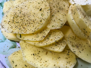 raw potatoes sprinkled with seasonings, cut into round pieces for boiling and baking