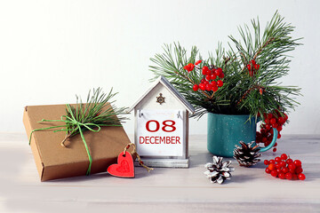 Calendar for December 8: a decorative house with the numbers 08, the name of the month December in English, a gift, a red heart, a New Year's decor on a light background