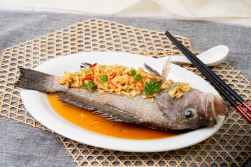 STEAMED GAROUPA IN TRADITIONAL SAUCE with chopsticks served in dish isolated on table top view of singapore food