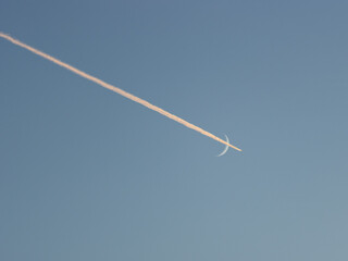 airplane flying through crescent moon