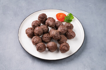 Fried meatballs on a white plate on a blue background. Meat meatballs cooked in the oven. The concept of healthy eating.