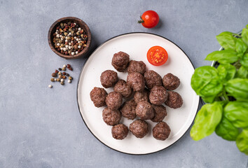 Fried meatballs on a white plate on a blue background with fresh herbs, tomatoes and spices. Meat meatballs cooked in the oven. The concept of healthy eating.