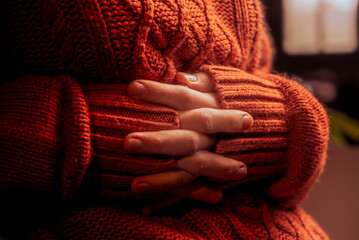 Fototapeta na wymiar female hands in a warm sweater, heat theme