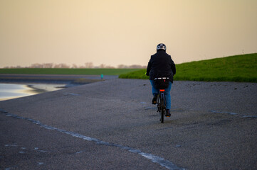 Woman on ebike cycling on a dyke on the North Sea shoreline