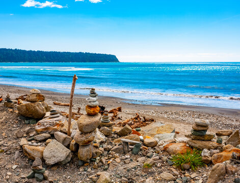 Rocks on the shore forming cairns and a view of the coastline of the South Island in the South Pacific Ocean; South Island, New Zealand