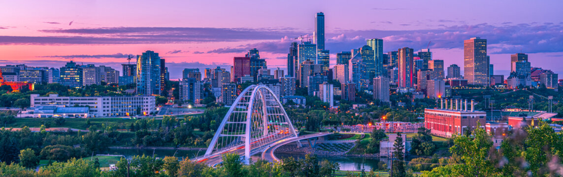 Skyline of Edmonton at dusk with a pink glow and the Walterdale Bridge crossing the North Saskatchewan River in the River Valley; Edmonton, Alberta, Canada