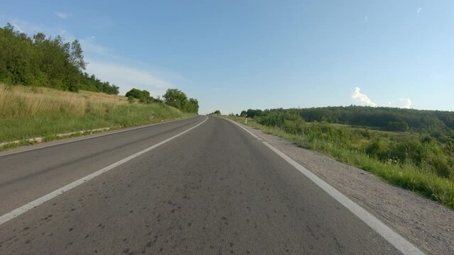 A Slow Car Or Motorcycle Ride Uphill On A Mountain Road Surrounded By Meadows And Trees. Blue Sky, Summer Time. POV Shot